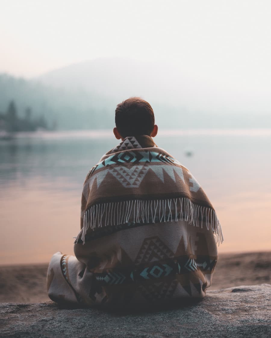 Man sitting down looking over a lake